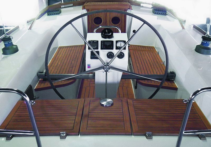 The teak-laid cockpit with a stainless-steel wheel and the engine instrument binnacle.