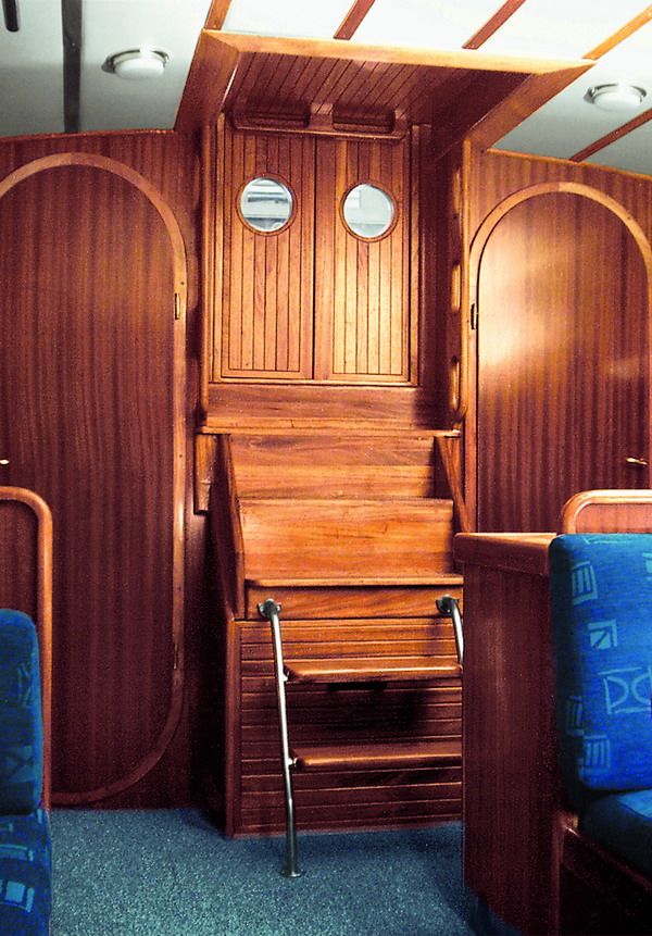 The solid mahogany companionway steps and main bulkhead with two round portlights.