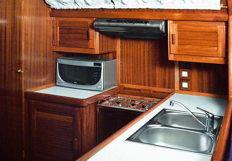 The galley in solid mahogany — gas cooker, microwave, stainless double sink and extractor.