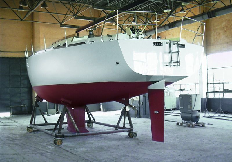 Stern quarter view of the hull on its cradle, showing the transom, skeg rudder and folding propeller.